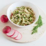 A healthy vegan salad with buckwheat, radish, and dill garnished with sesame seeds.